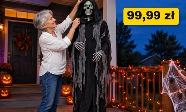 Kobieta ustawia na ganku o zmierzchu wysoką figurę kostuchy na Halloween, obok dynie ze światełkami