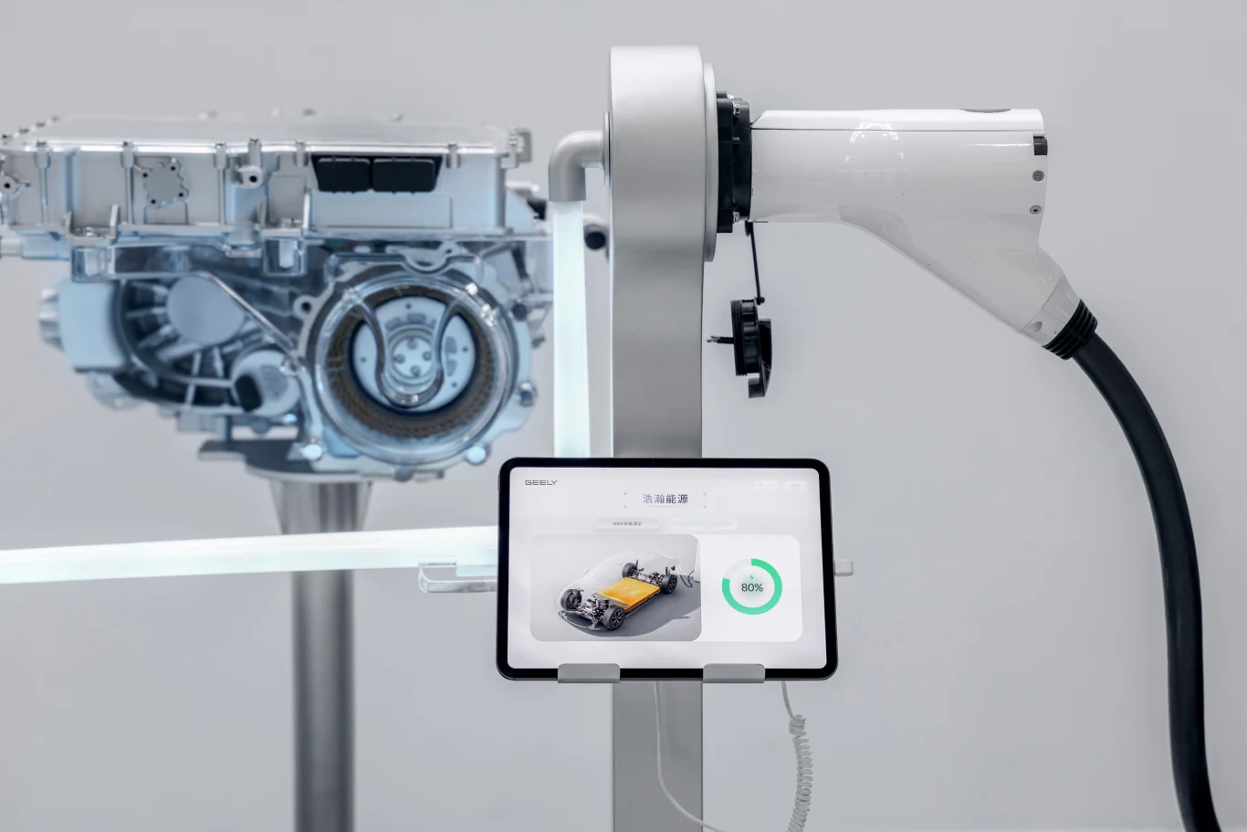 Nowy system system Xingrui PowerMind wykorzystuje m.in. sztuczną inteligencję. Fot. Geely Auto Group Stacja ładowania samochodów elektrycznych z podłączoną ładowarką oraz ekranem dotykowym wyświetlającym wizualizację i poziom naładowania pojazdu, obok widoczny silnik elektryczny.