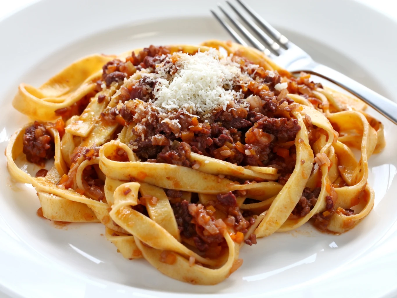 Makaron tagliatelle z sosem bolognese z mielonego mięsa oraz startym serem na wierzchu.