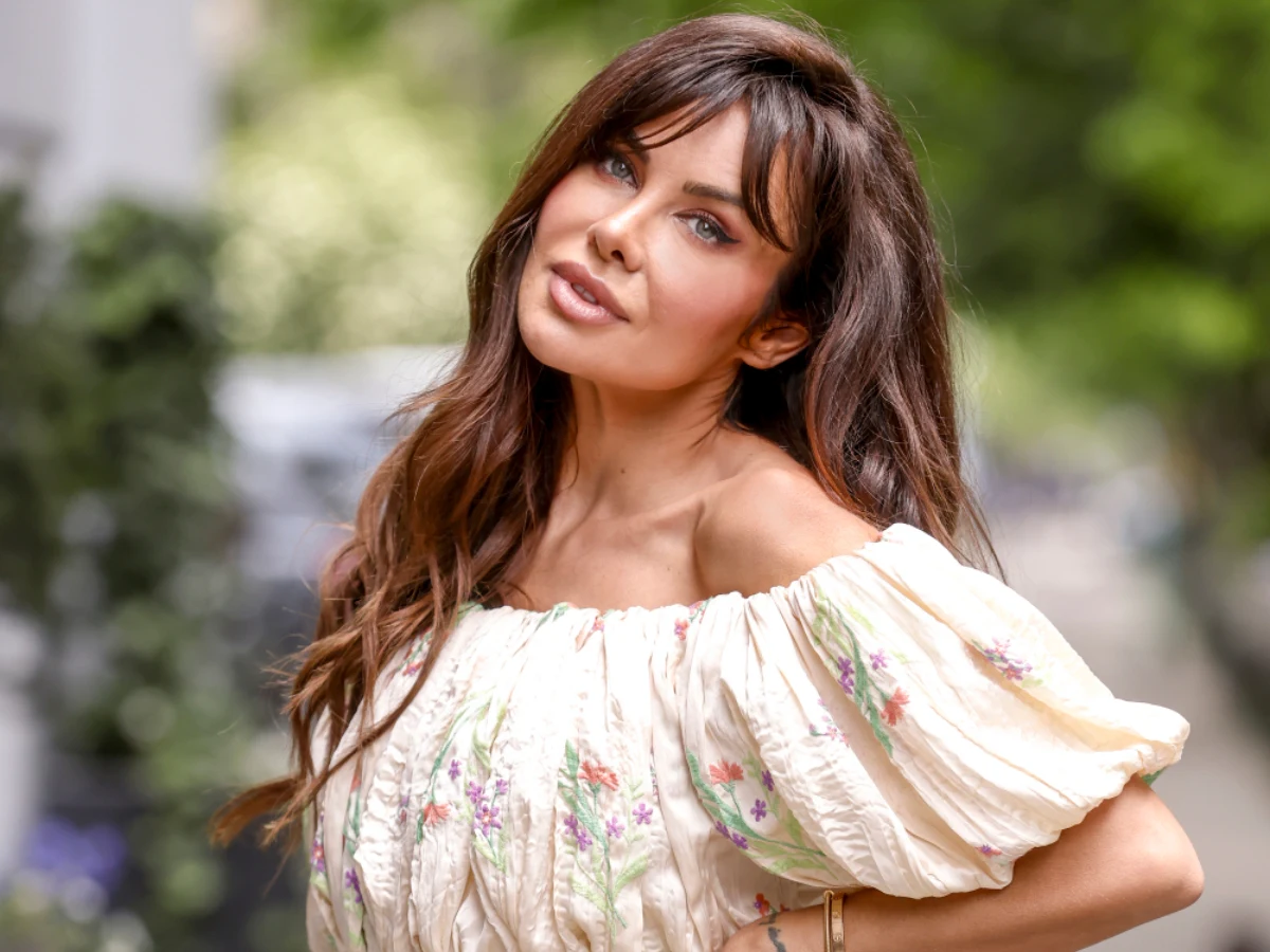 Natalia Siwiec Natalia Siwiec w kremowej bluzce z kwiatowym wzorem pozuje na świeżym powietrzu.