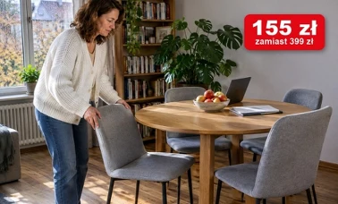 Kobieta dosuwa szare tapicerowane krzesło do okrągłego dębowego stołu w jasnej jadalni