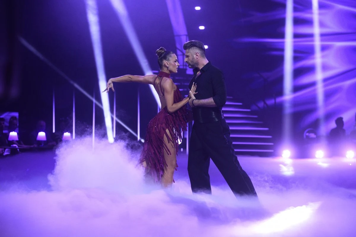 Piotr Gumulec i Julia Suryś Para tancerzy wykonuje zmysłowy układ taneczny na scenie wypełnionej dymem i fioletowym światłem, zbliżając się do siebie w intensywnym spojrzeniu.