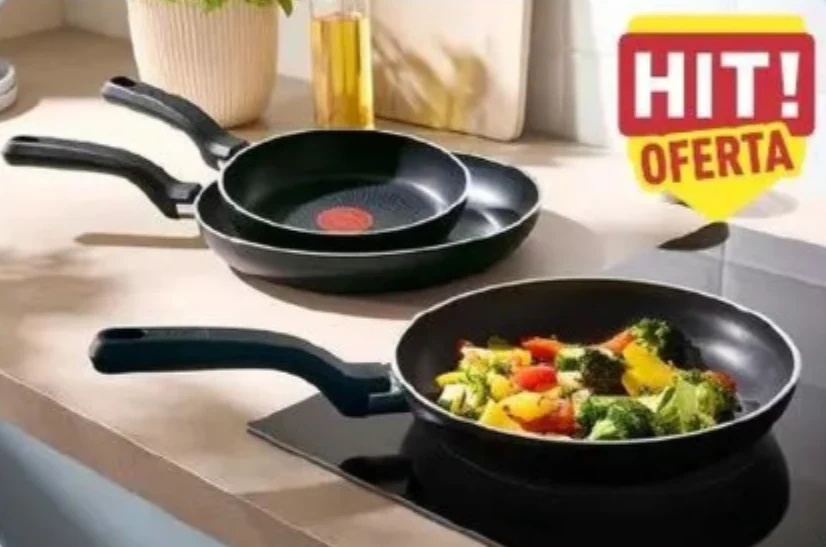 Tefal w Aldi od 59,99 zł. Są trzy rozmiary patelni Trzy patelnie, z których jedna znajduje się na płycie grzewczej z podsmażanymi warzywami, obok nich żółto-czerwona etykieta z napisem 'HIT! OFERTA'.