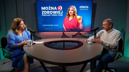 Dwie osoby rozmawiające przy okrągłym stole w studiu nagraniowym, z mikrofonami i kubkami, na ekranie w tle grafika promująca podcast „Można Zdrowiej” z kobietą trzymającą pomarańczę.