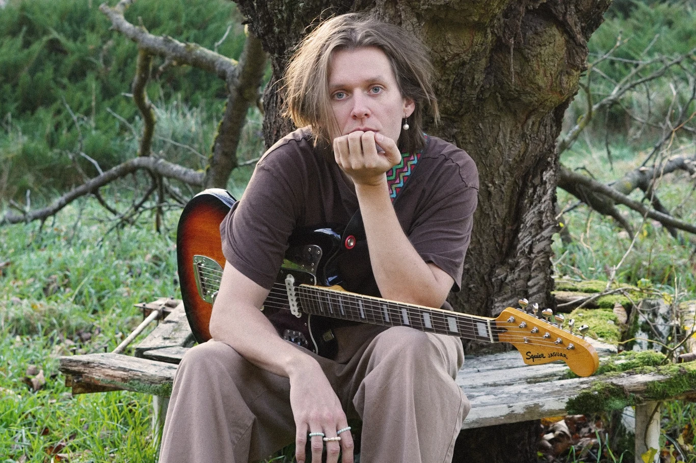 Oysterboy wydał drugi album - "Eskapizm" Oysterboy siedzi z elektryczną gitarą na ławce przy starym drzewie, promując album 'Eskapizm'.