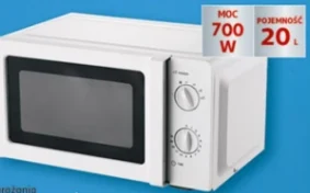 Biała kuchenka mikrofalowa z dwoma pokrętłami do ustawiania czasu i mocy, oznaczenie mocy 700 W oraz pojemności 20 litrów na etykiecie na niebieskim tle.