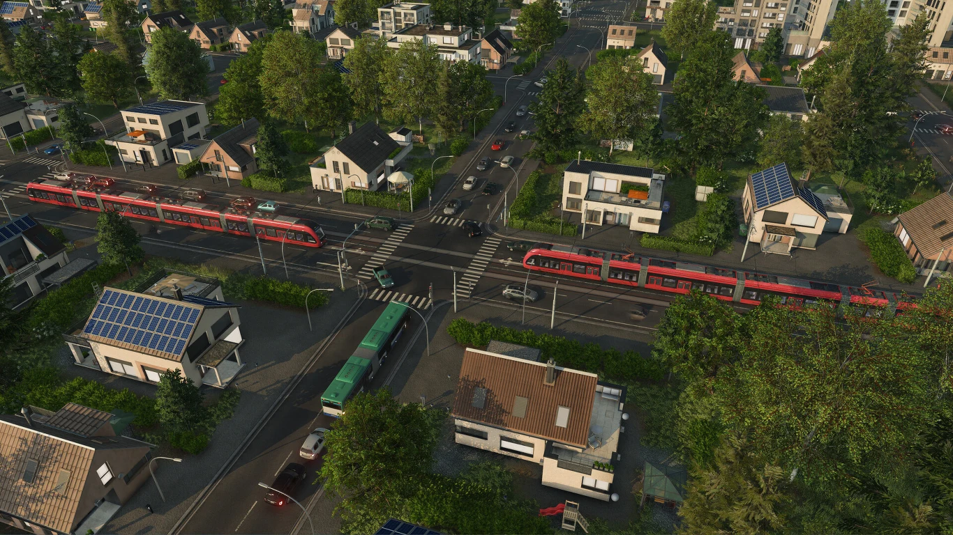Transport Fever 3 Dworzec kolejowy z czerwonymi pociągami oraz zielonym autobusem na skrzyżowaniu w otoczeniu nowoczesnych domów jednorodzinnych z panelami słonecznymi na dachach, wśród licznych drzew i zadbanych ulic.