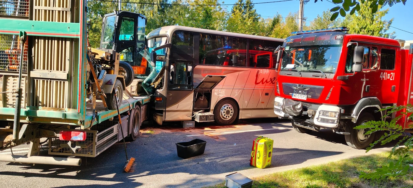 Uszkodzony autokar na miejscu wypadku w Osowcu. Obok pojazdu stoją samochód ciężarowy i wóz straży pożarnej.