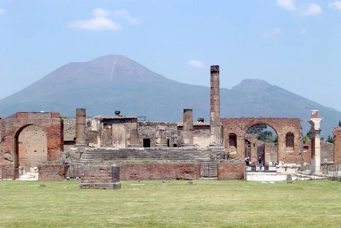 Przełom w geologii. Zapisy historyczne sprzed 2000 lat poprawiły dokładność datowania erupcji Wezuwiusza Ruiny starożytnej areny z murami i kolumnami na tle łagodnych zboczy Wezuwiusza.