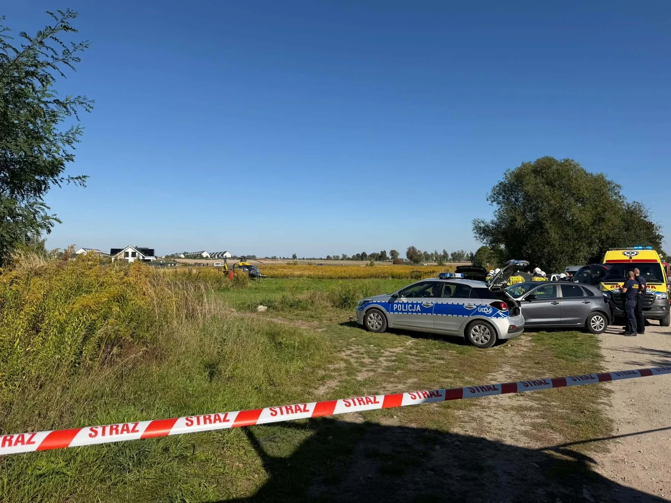 Pod Poznaniem doszło do potrącenia trzech osób, jedna z nich zmarła. Policja bada sprawę Policja i karetka na polnej drodze pod Poznaniem, teren zdarzenia zabezpieczony taśmą, obecni funkcjonariusze.