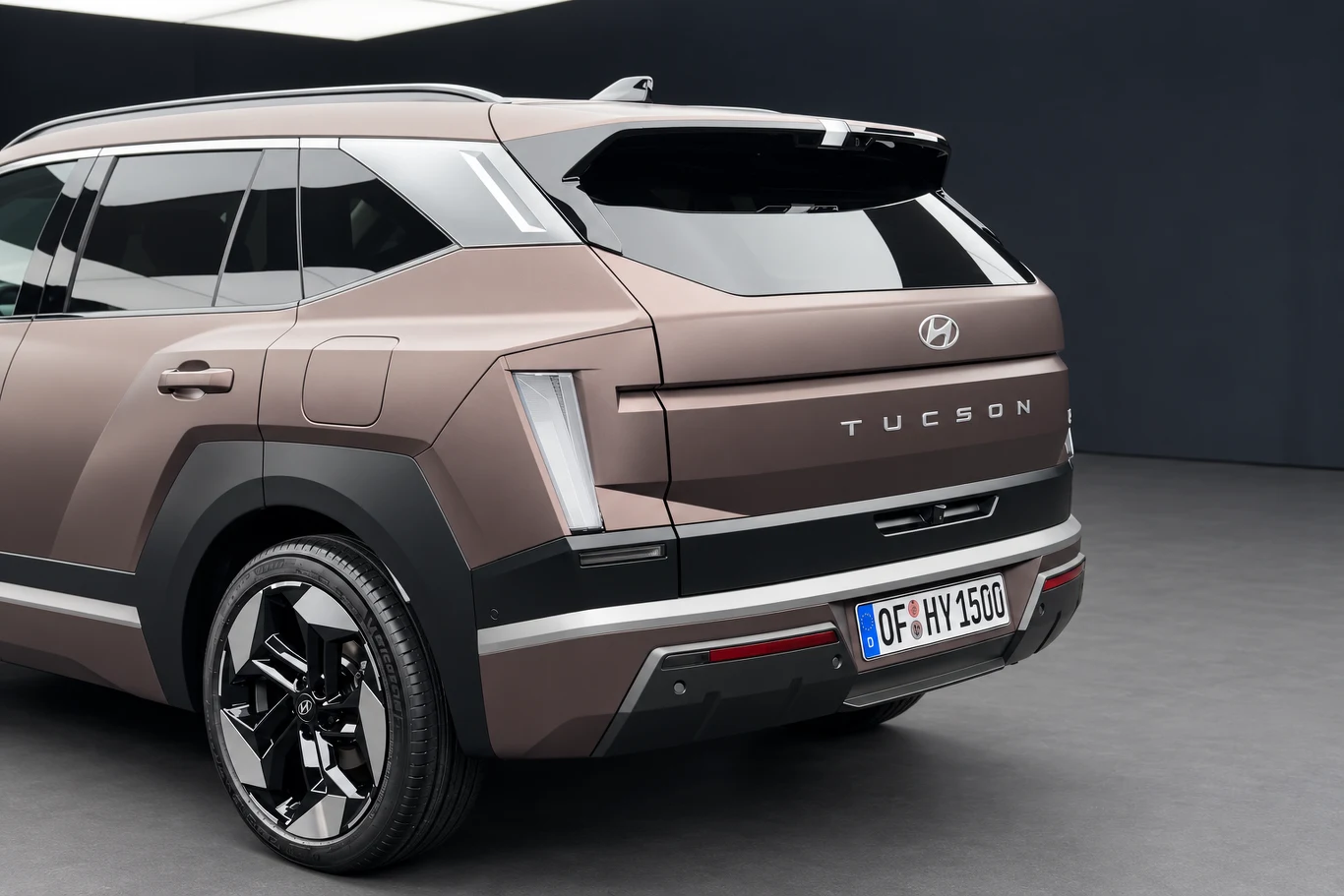 Po zgaszeniu świateł klosze tylnych lamp stają się zupełnie przezroczyste. Tylny fragment nowoczesnego SUV-a Hyundai Tucson w metalicznym brązowym kolorze z wyrazistymi liniami nadwozia, charakterystycznymi światłami LED oraz czarnymi, błyszczącymi felgami.