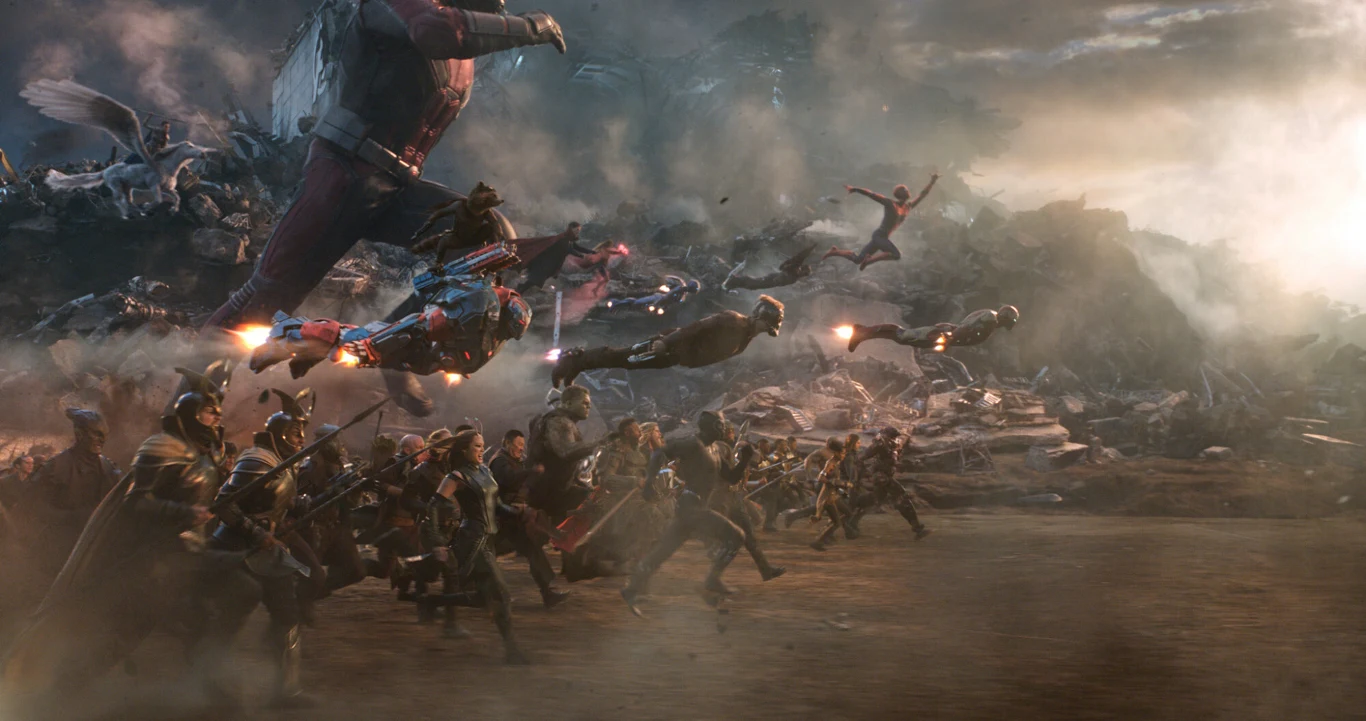 Kadr z filmu "Avengers: Koniec gry" Kadr z filmu Avengers: Koniec gry. Superbohaterowie biegną i lecą przez pole bitwy wśród ruin i dymu.