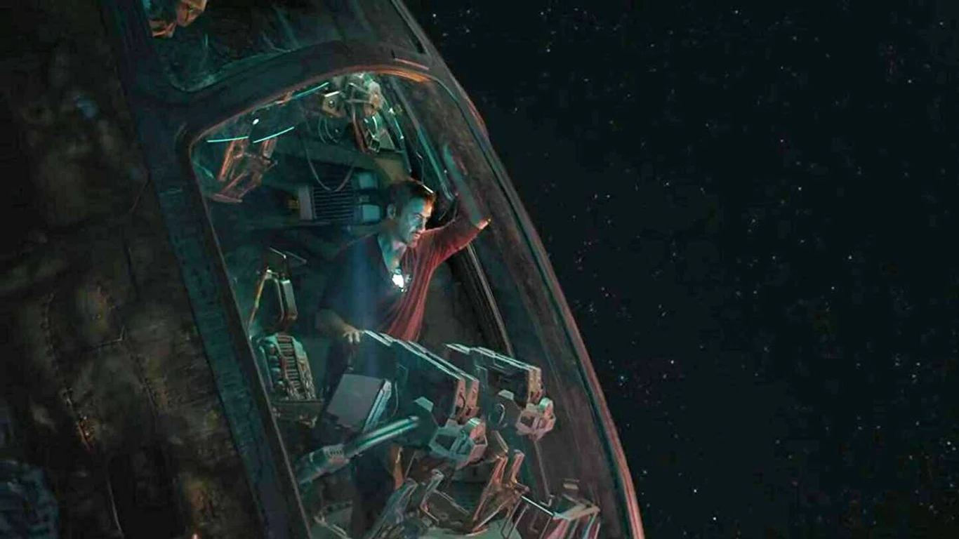 Kadr z filmu "Avengers: Koniec gry" Człowiek ubrany w czerwony pelerynę siedzi wewnątrz futurystycznego statku kosmicznego, spoglądając przez duży panoramiczny kokpit na otwartą przestrzeń kosmiczną wypełnioną gwiazdami.