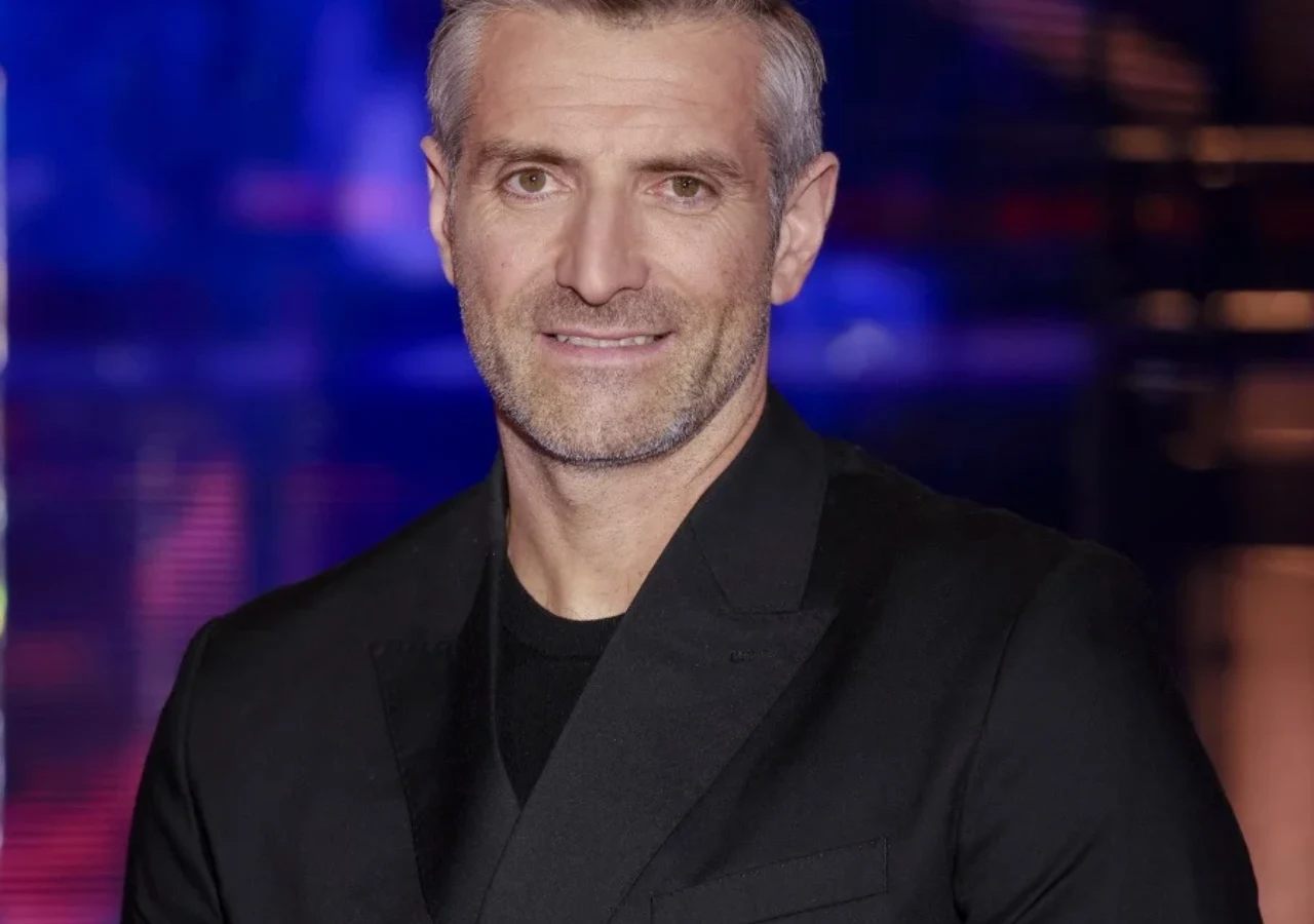 Maciej Dowbor Portret Macieja Dowbora w eleganckiej czarnej marynarce. Mężczyzna ma krótkie, siwiejące włosy oraz zarost.