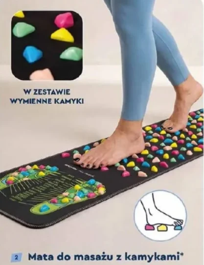 Mata do masażu Osoba stoi boso na czarnej macie pokrytej kolorowymi, wymiennymi kamykami przeznaczonymi do masażu stóp.
