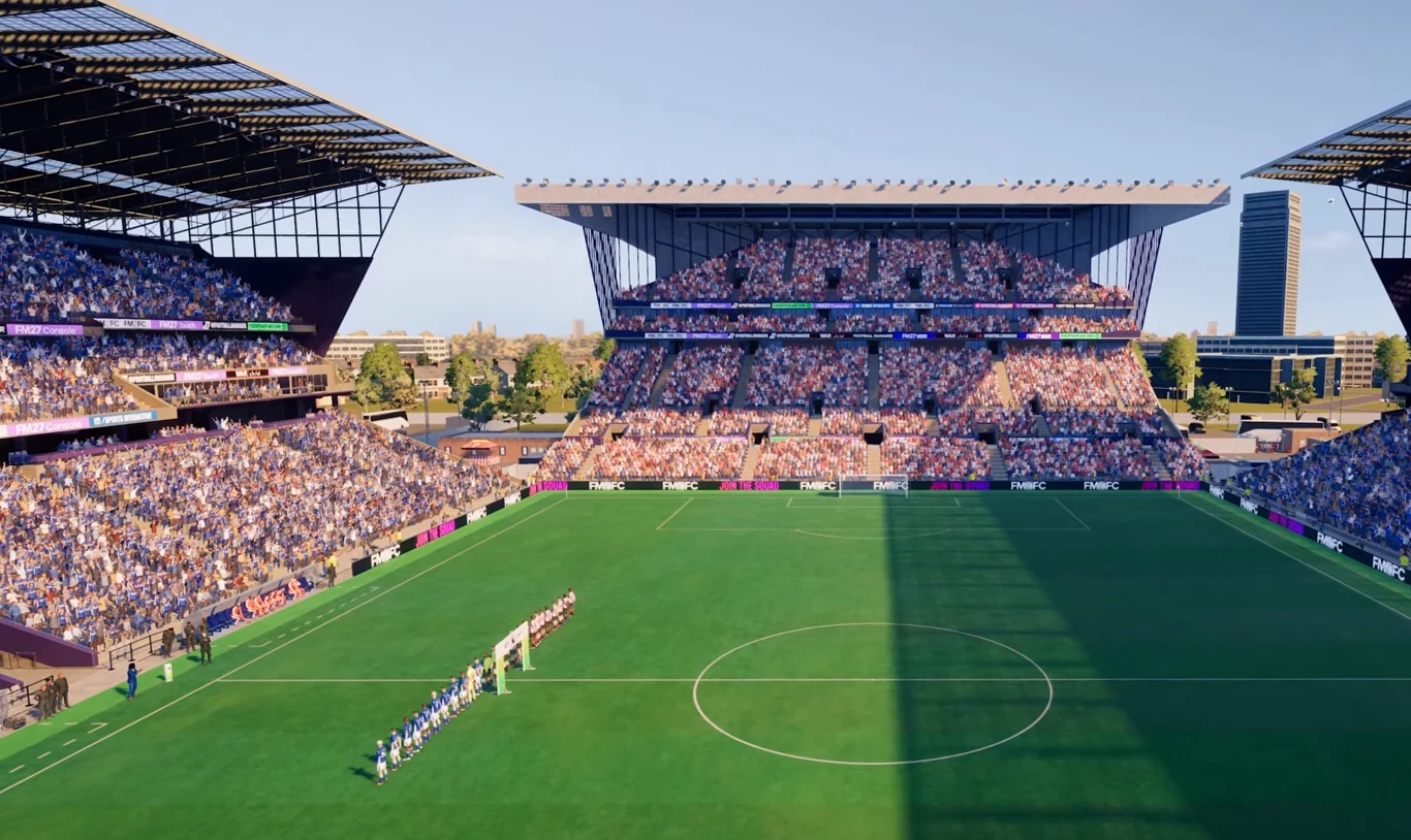 Football Manager 27 Football Manager 27. Dwie drużyny piłkarskie ustawione na środku nowoczesnego stadionu przed trybunami.