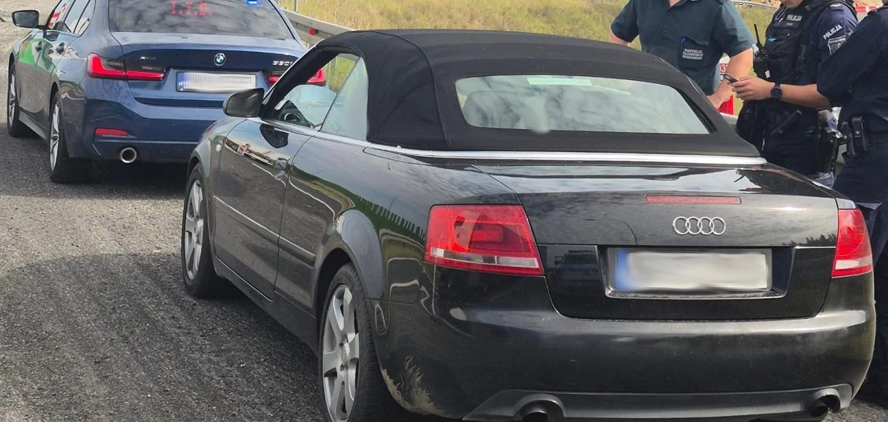 Kierowca Audi A4 Cabrio zatrzymany przez funkcjonariuszy CANARD-u znacząco przekroczył prędkość, a do tego był pijany i nie miał prawa jazdy Czarny kabriolet Audi zatrzymany na poboczu drogi, za nim nieoznakowany radiowóz BMW oraz trzech umundurowanych policjantów prowadzących interwencję.