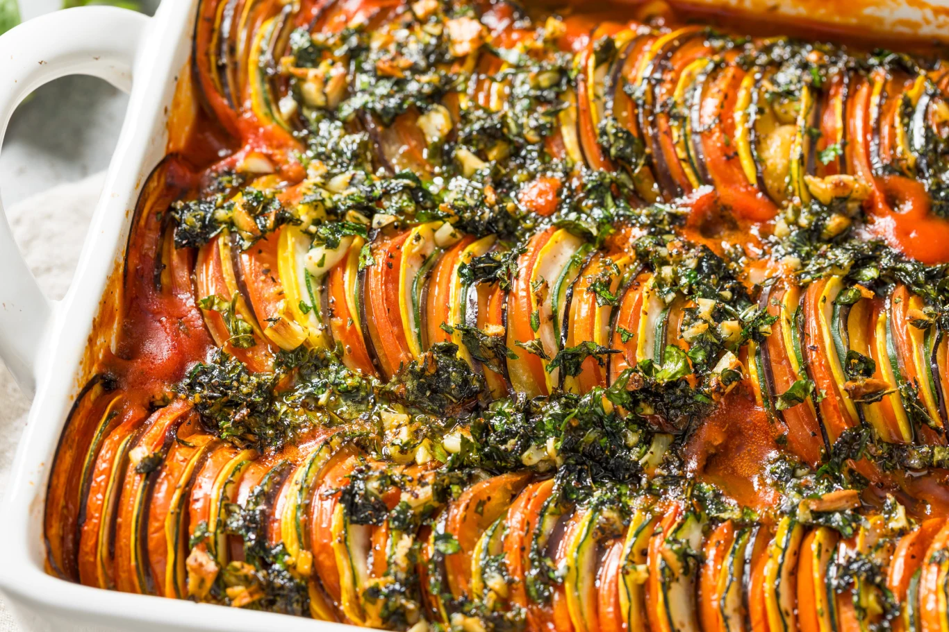 Zapiekanka ratatouille zachwyci każde podniebienie. Pięknie pachnie ziołami, a najpyszniejszy jest sos Zapiekanka ratatouille z plastra cukinii, bakłażana i pomidora, zapieczona w sosie ziołowym i posypana świeżymi ziołami.