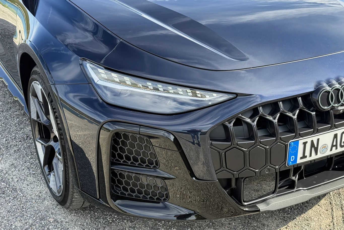 Przód czarnego Audi z wyrazistym, sześciokątnym grillem, reflektorem LED oraz detalami o sportowym charakterze.
