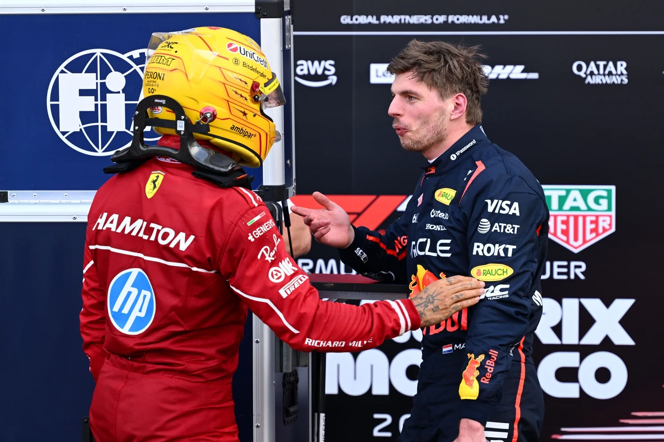 Lewis Hamilton i Max Verstappen, 24.05.2025 r. Lewis Hamilton w czerwonym kombinezonie Ferrari i Max Verstappen w granatowym Red Bullu ściskają dłonie