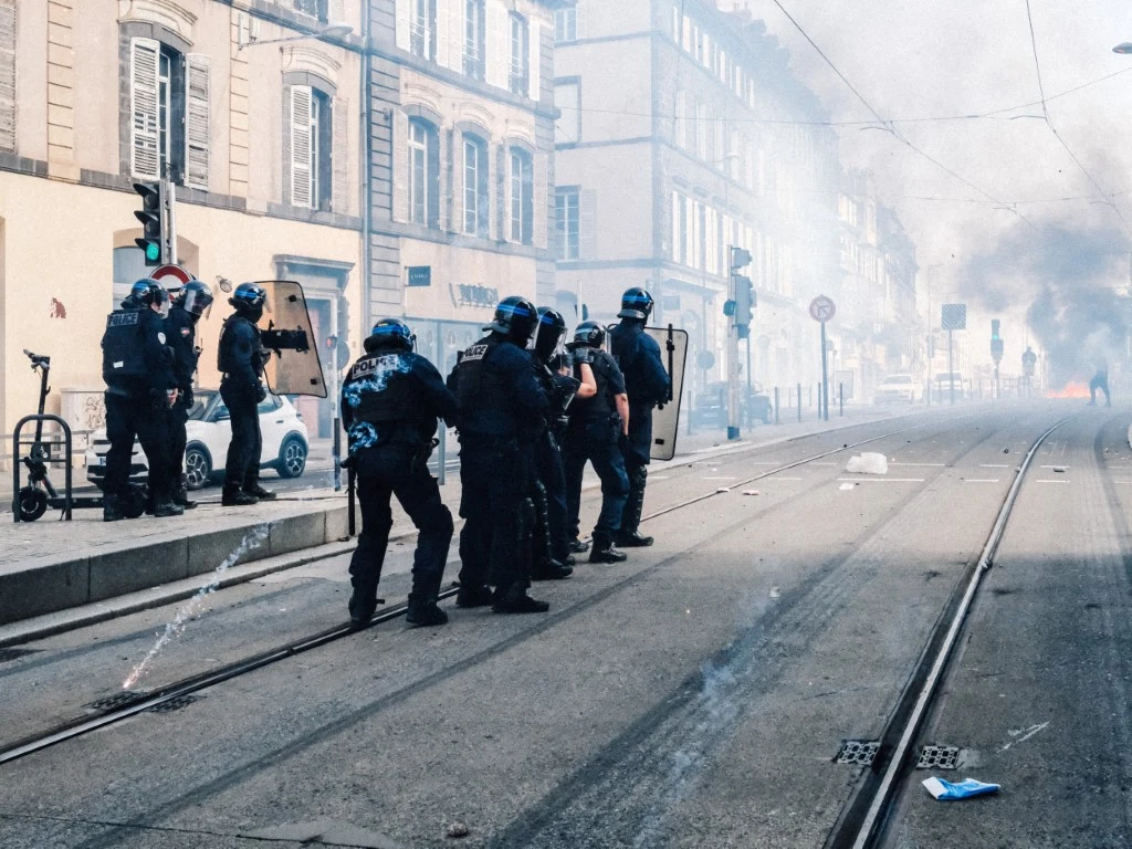 We Francji płoną licea. To dramatyczna wiadomość dla Europy Policjanci w kaskach i z tarczami na ulicy, obok torów tramwajowych, w tle dym i zniszczona jezdnia.