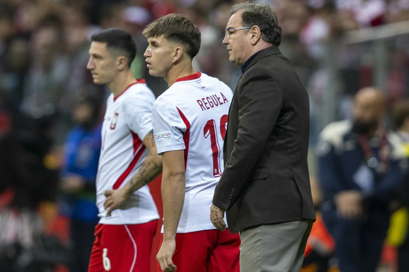 Marcel Reguła znów jest na celowniku Borussii Dortmund Marcel Reguła i drugi piłkarz w białych strojach oraz trener stoją na boisku podczas meczu.