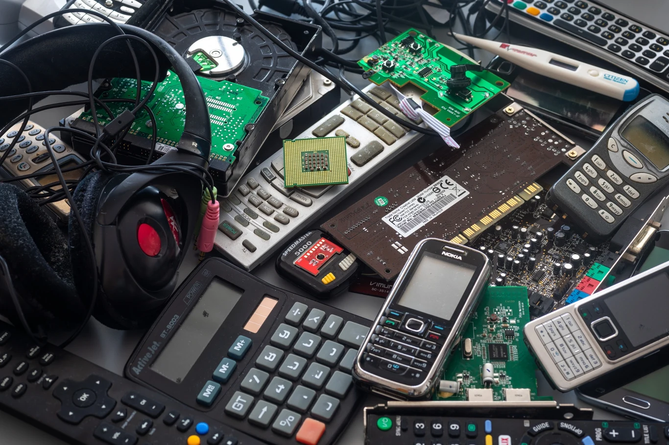 Gdzie wyrzucić starą elektronikę w Gliwicach? Miasto przygotowało mobilny punkt zbiórki. Stare telefony, kalkulatory, piloty, podzespoły elektroniczne i słuchawki ułożone razem jako elektroodpady.