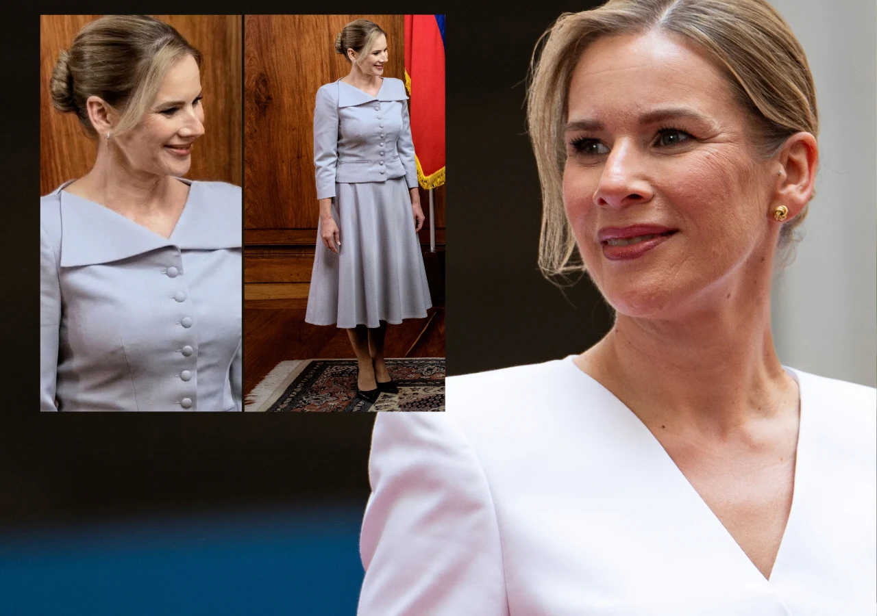 Kobieta w eleganckim, jasnym kostiumie o klasycznym kroju z rozkloszowaną spódnicą, spięte włosy, subtelny makijaż i złote kolczyki; tło stanowi wnętrze z drewnianą ścianą oraz ciemnoniebieskim elementem.