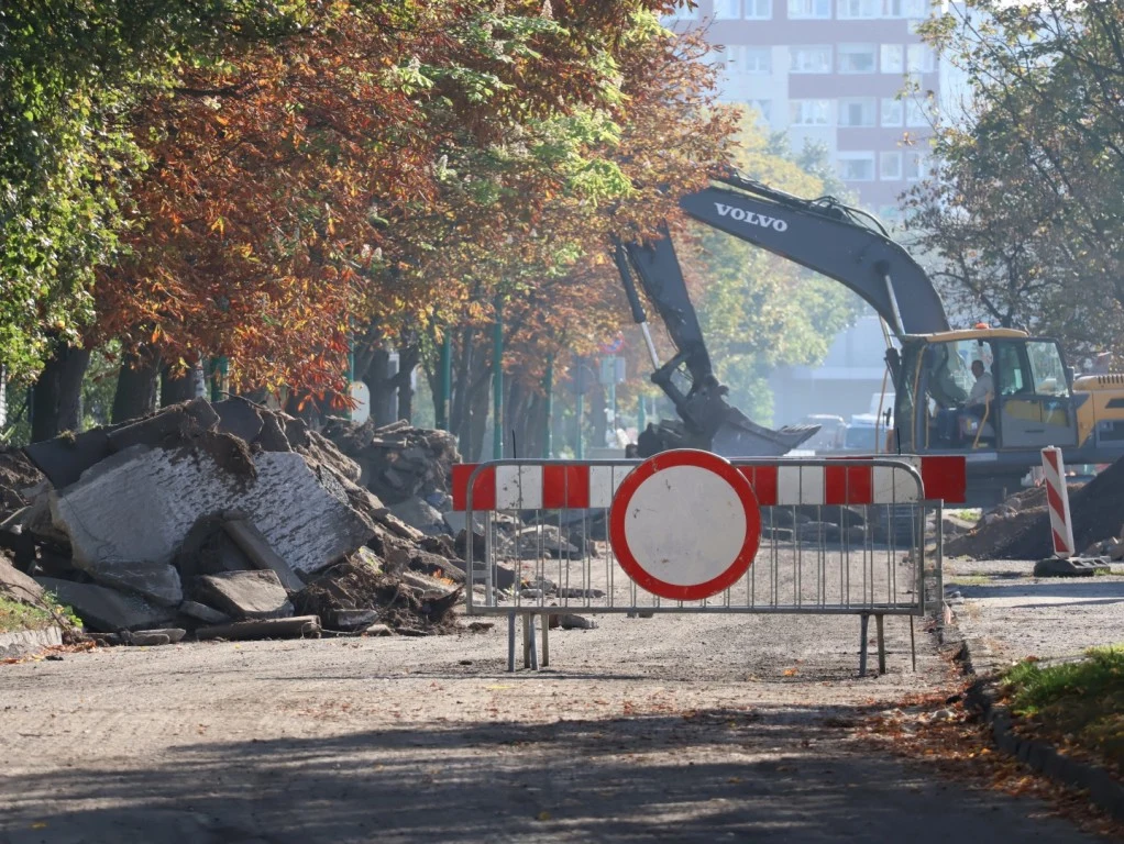Remont ulicy w Legnicy. Urząd miasta wystosował pilny apel do mieszkańców. Zdjęcie ilustracyjne Remont ulicy Górniczej w Legnicy: koparka, bariera z zakazem wjazdu, zniszczony asfalt, drzewa jesienią.