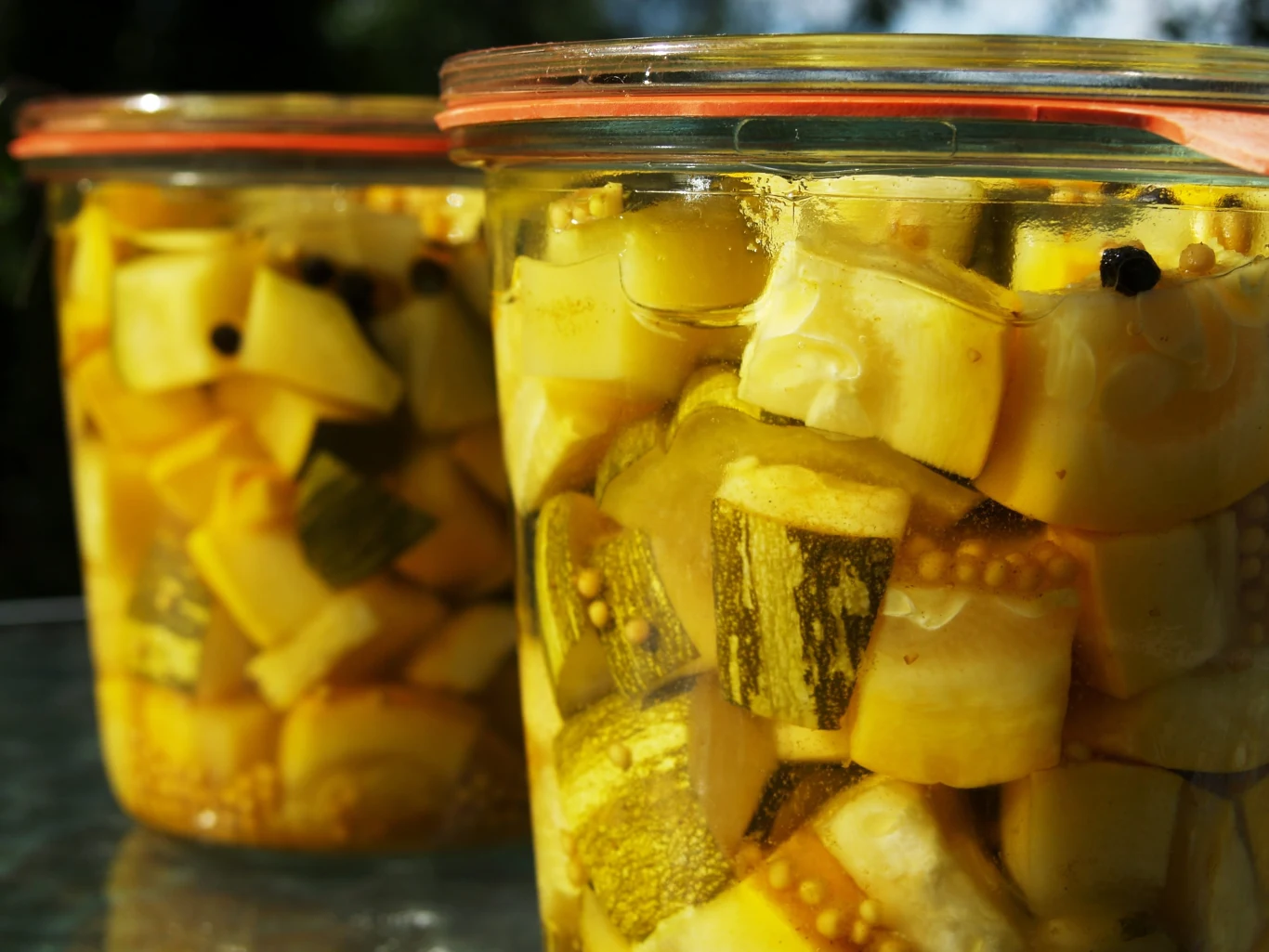 Cukinia z pieczarkami po litewsku. Pyszny dodatek do obiadu bez pasteryzowania Szklany słoik z kawałkami marynowanej cukinii i pieczarek w zalewie octowej z przyprawami.