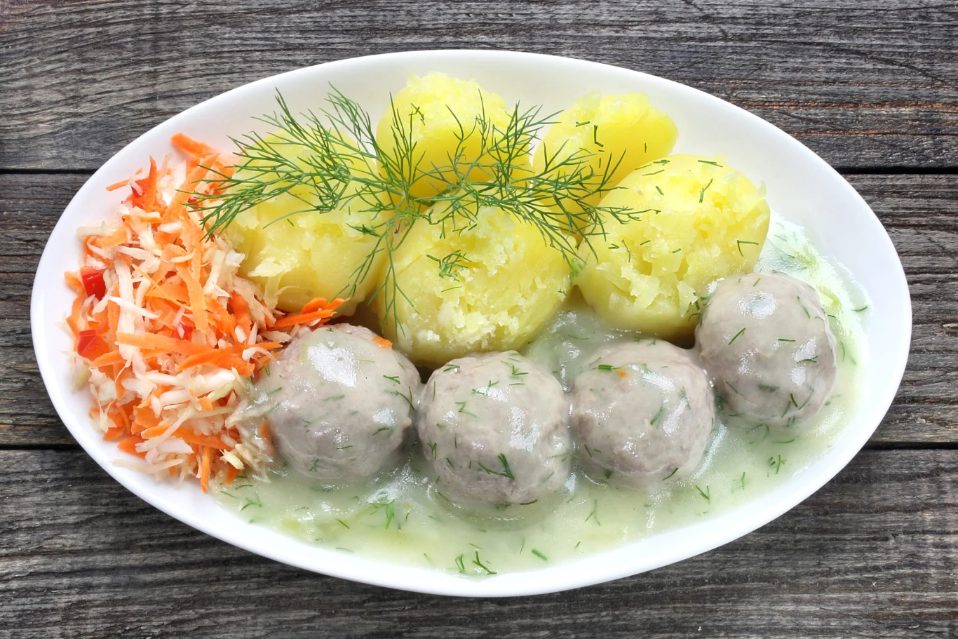 Klopsiki w sosie koperkowym to znakomite danie obiadowe nie tylko dla dzieci Trzy pulpety z indyka w jasnym sosie koperkowym, ziemniaki z koperkiem i surówka z kapusty i marchewki.