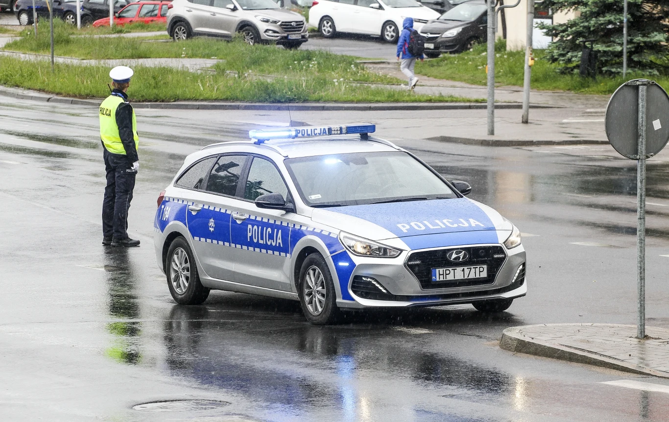 Policja w Olsztynie zwraca uwagę na stan zdrowia kierowców. Doszło do dwóch groźnych zdarzeń. Radiowóz policyjny Hyundai i30 i policjant na mokrej jezdni podczas kontroli ruchu w Olsztynie