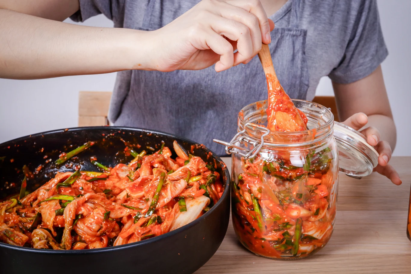 Kimchi to niskokaloryczna kiszonka, pełna witamin, minerałów i błonnika. Domowe przygotowanie kimchi – mieszanka warzyw z przyprawami wkładana do szklanego słoika.