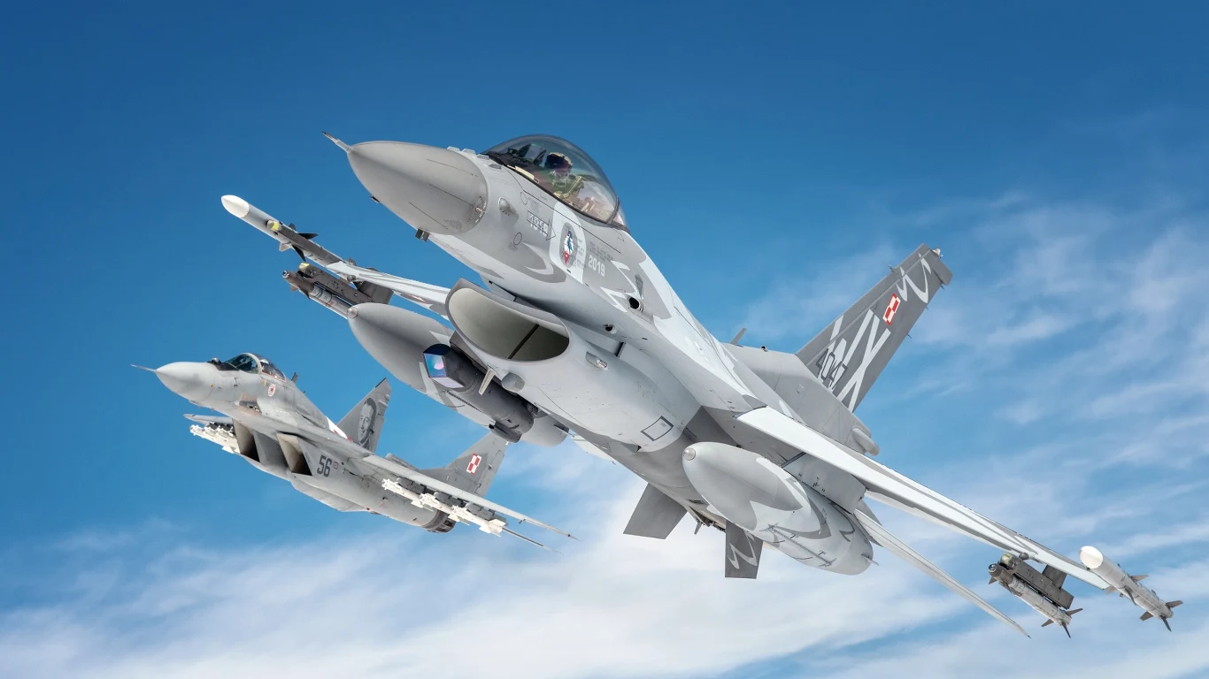 Rządowe Centrum Bezpieczeństwa rozesłało alerty w związku z rosyjskim atakiem w Ukrainie Dwa myśliwce F-16 z biało-czerwonymi szachownicami lecące w szyku na tle błękitnego nieba.