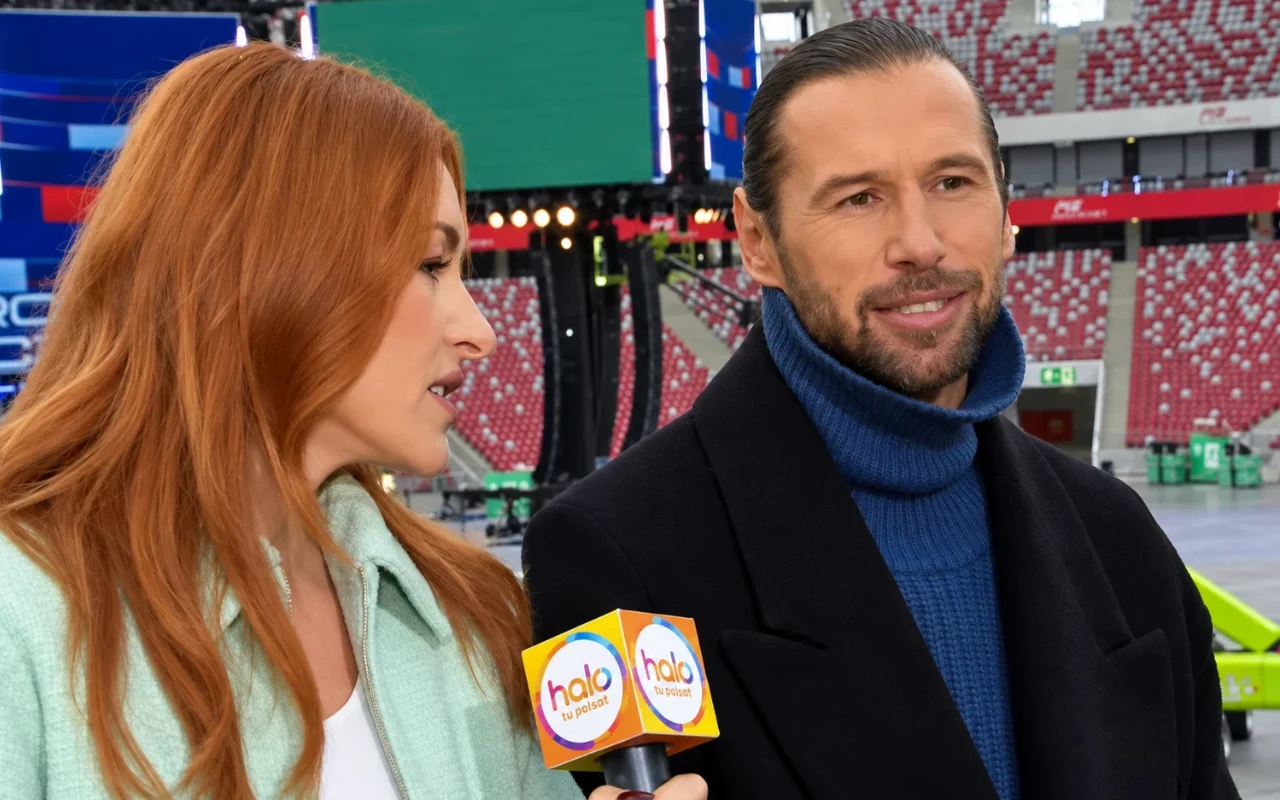 Dwoje osób rozmawia podczas wywiadu na stadionie, kobieta trzyma mikrofon z logo 'halo'.
