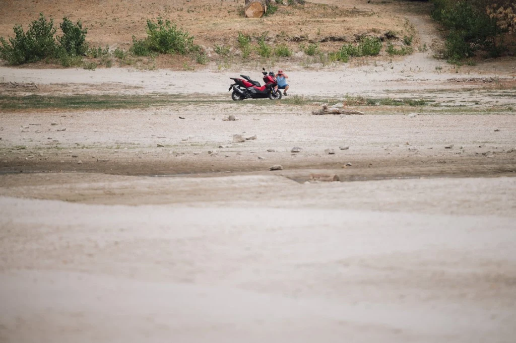 Dwa motocykle zaparkowane na pustym, suchym terenie z niewielką ilością zieleni w tle.