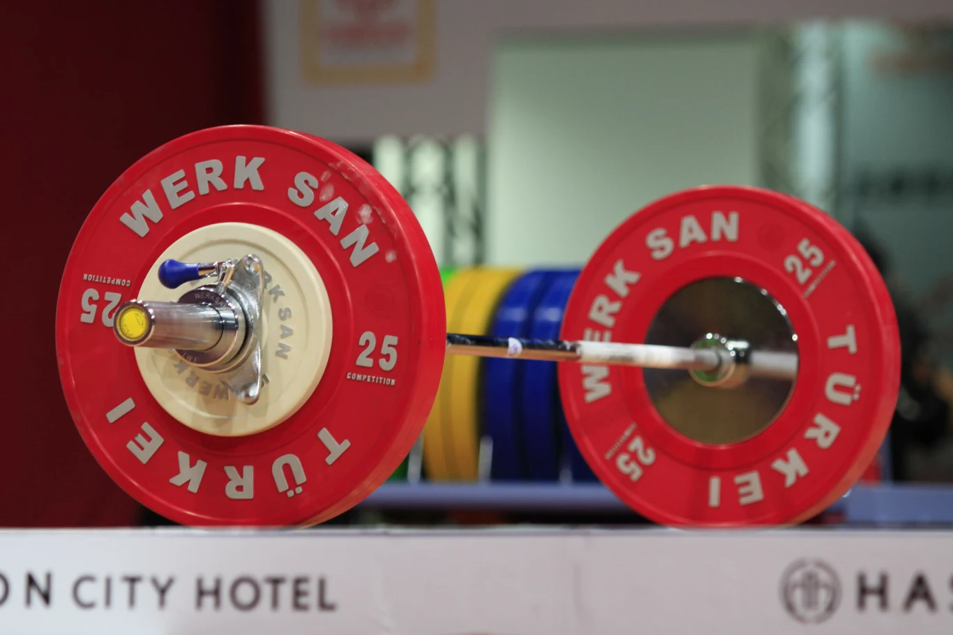Legniczanin triumfował podczas European Police & Fire Games 2026 Sztanga olimpijska z czerwonymi talerzami 25 kg na podłodze w siłowni podczas zawodów siłowych.