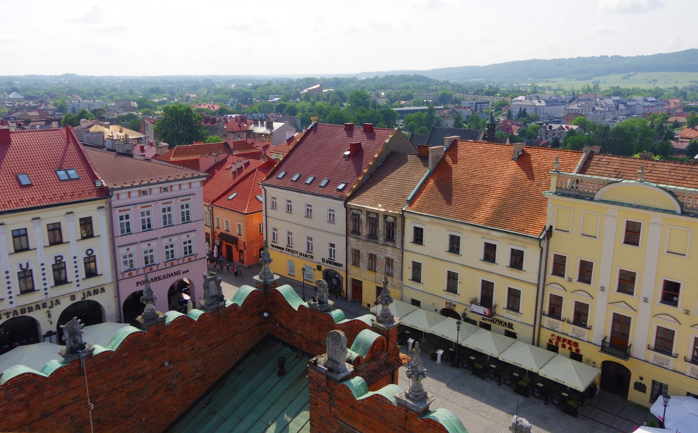 Mieszkanie za remont w Tarnowie. Miasto przygotowało 15 lokali. Kolorowe, zabytkowe kamienice z czerwonymi dachami wokół rynku w Tarnowie, w tle zielone wzgórza