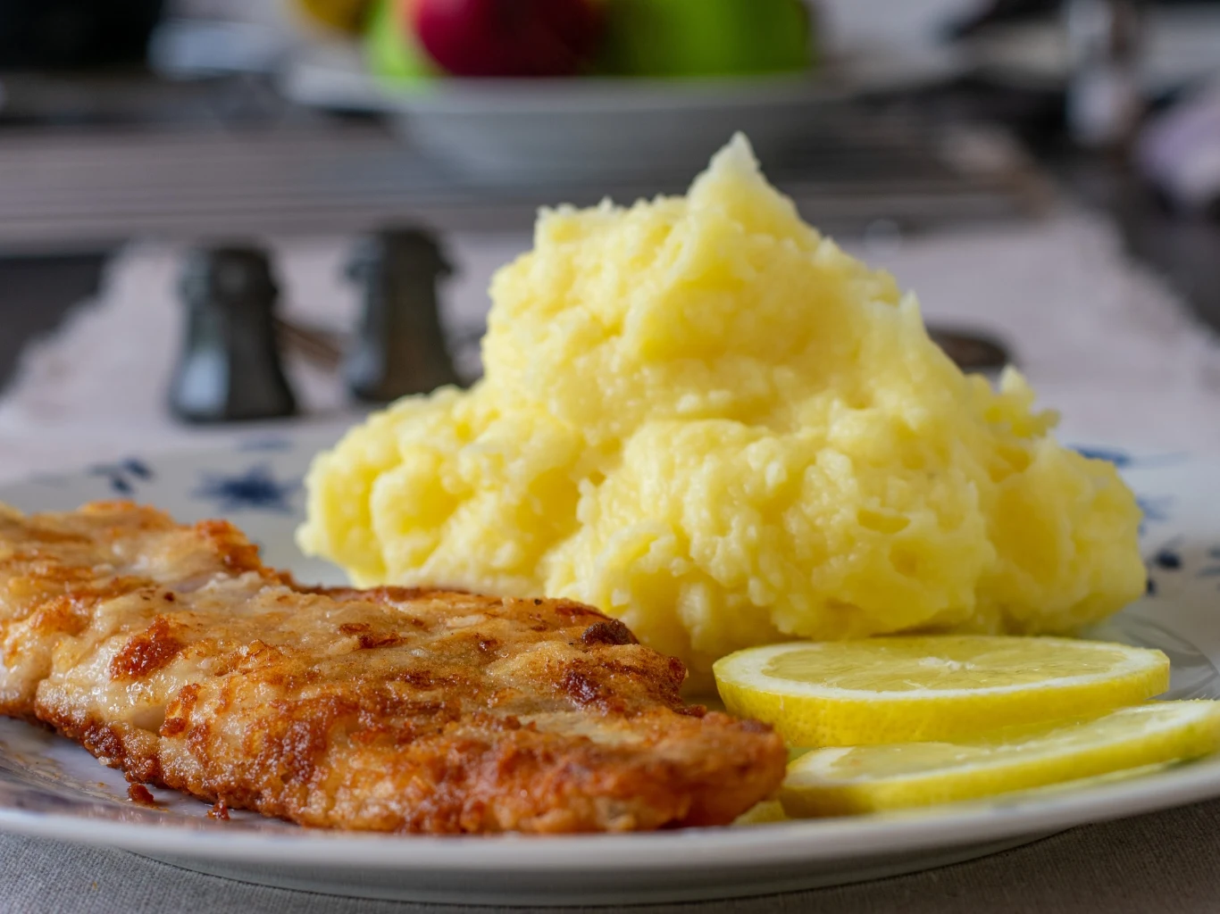 Miętus to jedna z najczystszych i najsmaczniejszych polskich ryb. Szkoda, że zapomniana. Panierowany filet miętusa z porcją puree ziemniaczanego i plasterkami świeżej cytryny na talerzu.