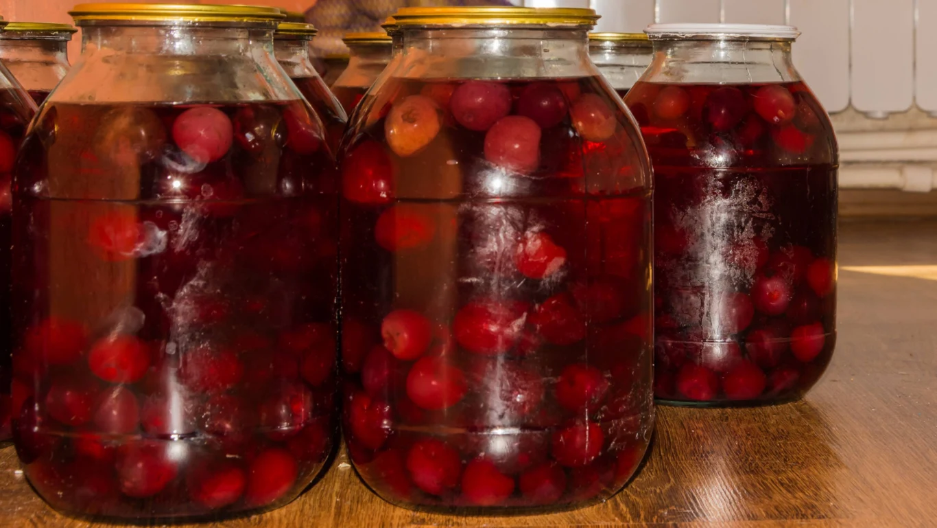 Kompot z winogron smakuje każdemu Słoiki z kompotem z winogron ustawione na drewnianej podłodze