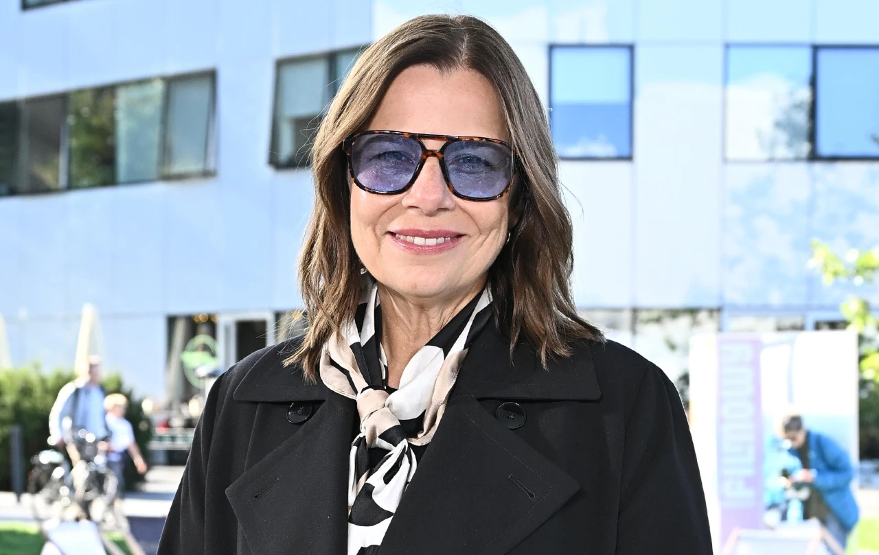 Agata Kulesza - gwiazda ożywiła jesienną stylizację z płaszczem w roli głównej za pomocą jasnej, kontrastowej apaszki Agata Kulesza w czarnym płaszczu i czarno-białej apaszce na tle szklanego budynku