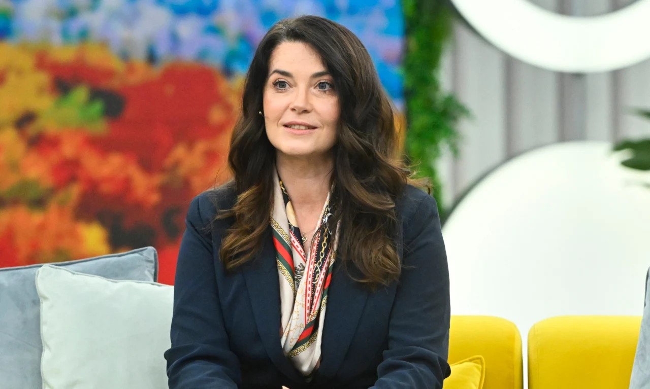 Agnieszka Salach w "halo tu polsat" zaprezetowała się w granatowej marynarce, którą ożywiła jasną apaszką Kobieta z długimi, ciemnymi włosami ubrana w granatową marynarkę i kolorową apaszkę siedzi na kanapie, w tle widoczne intensywne kolory i roślinność.