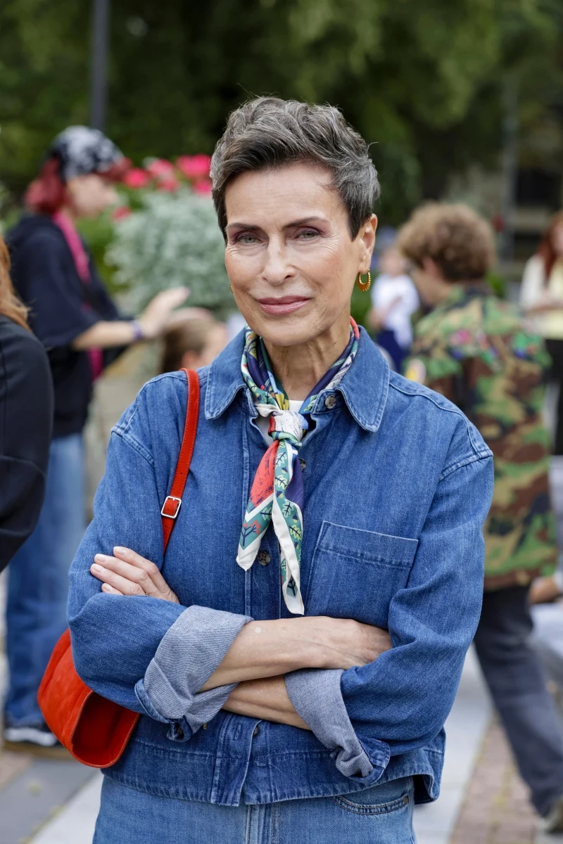Danuta Stenka na planie filmu pojawiła się w dżinsowej koszuli. Smaku stylizacji dodała czerwona torebka i apaszka z mocnym akcentem kolorystycznym Elegancka kobieta z krótkimi, siwiejącymi włosami w dżinsowej koszuli i kolorowej apaszce, z założonymi rękami i czerwoną torebką przewieszoną przez ramię.