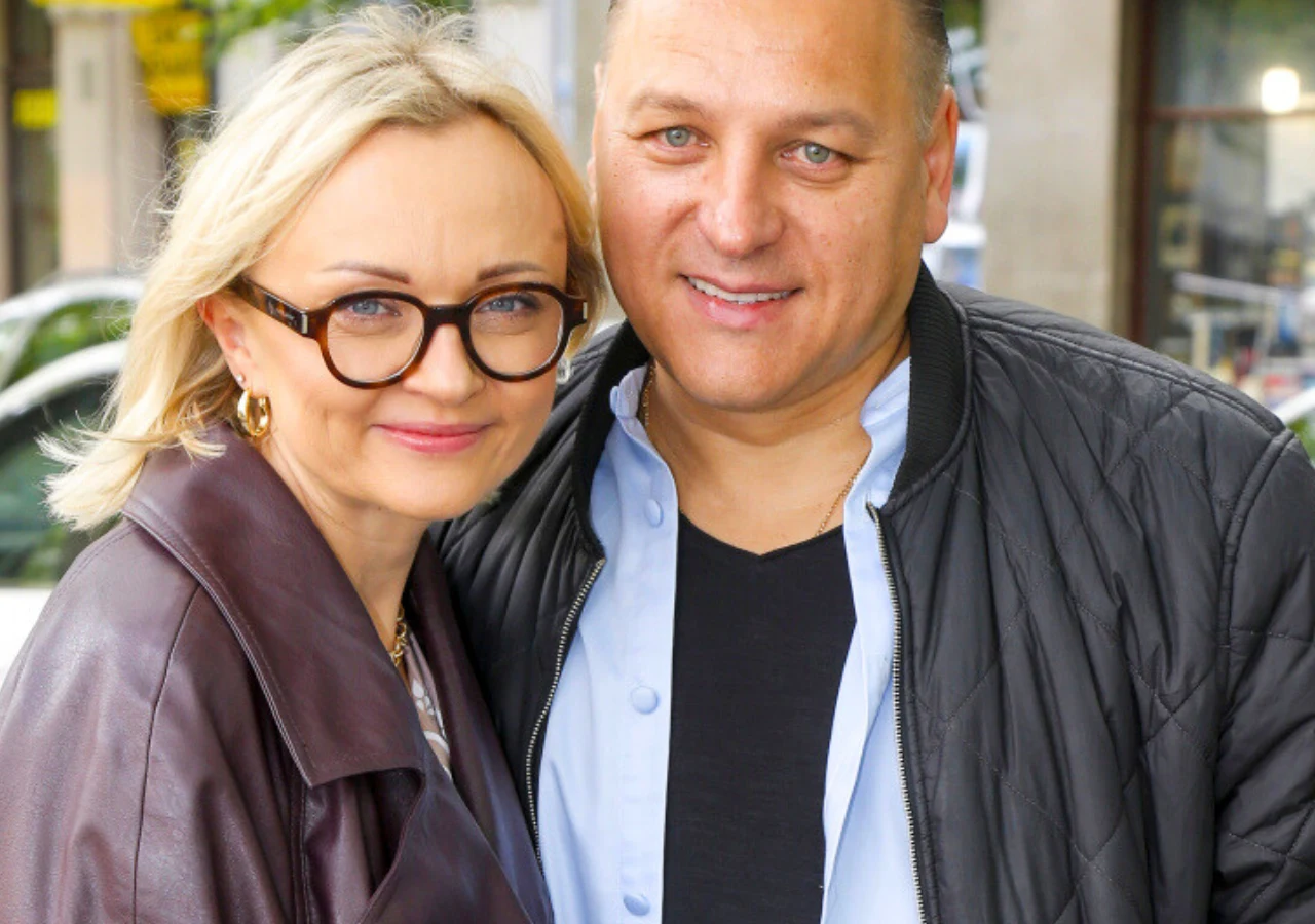 Edyta Golec, Łukasz Golec Uśmiechnięta para w średnim wieku stoi blisko siebie, ona ma jasne włosy, okulary i skórzaną kurtkę, on ubrany w czarną kurtkę i jasnoniebieską koszulę.