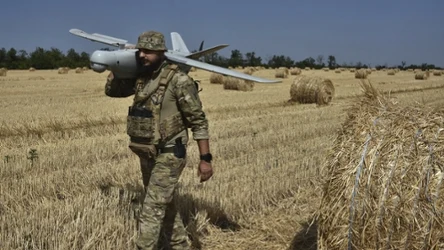Ukraiński żołnierz z dronem na polu pszenicy. Wojna w Ukrainie ogranicza zbiory