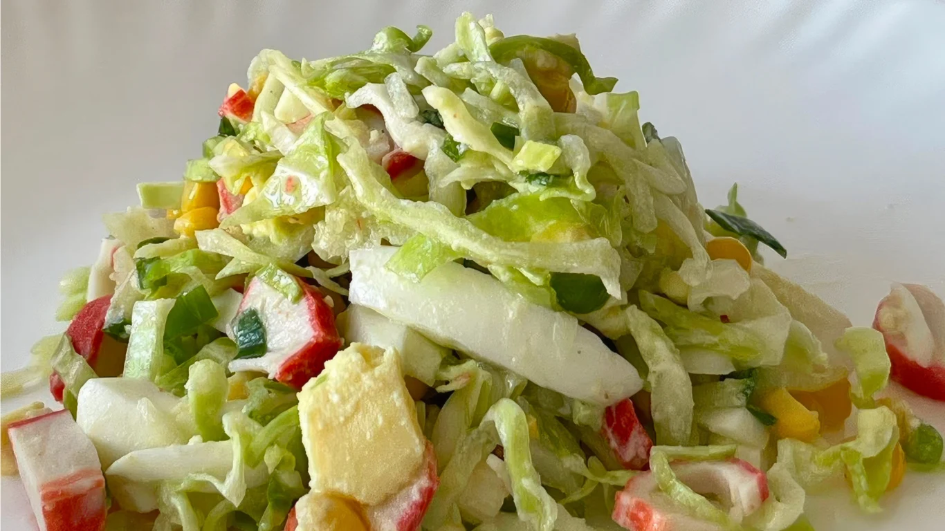 Sałatka z kapustą pekińską i surimi to świetna przystawka na imieniny Sałatka z kapustą pekińską, surimi, awokado, papryką, ogórkiem i sałatą lodową z jasnym sosem na talerzu