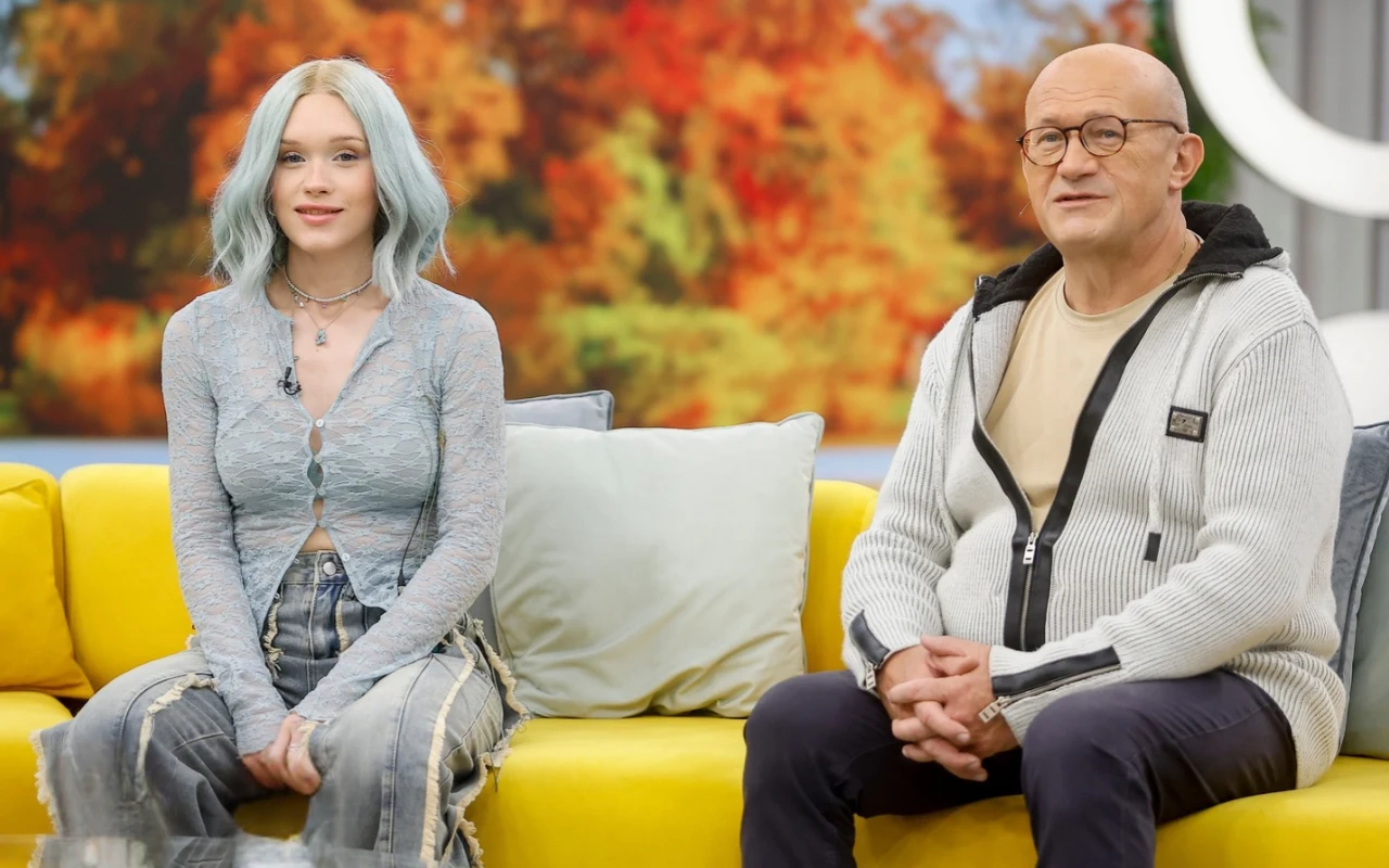 Bryska z tatą w "halo tu polsat" Dwie osoby siedzą na żółtej kanapie; młoda kobieta z jasnoniebieskimi włosami oraz starszy mężczyzna w okularach i jasnym swetrze, w tle rozmyty obraz jesiennych drzew.