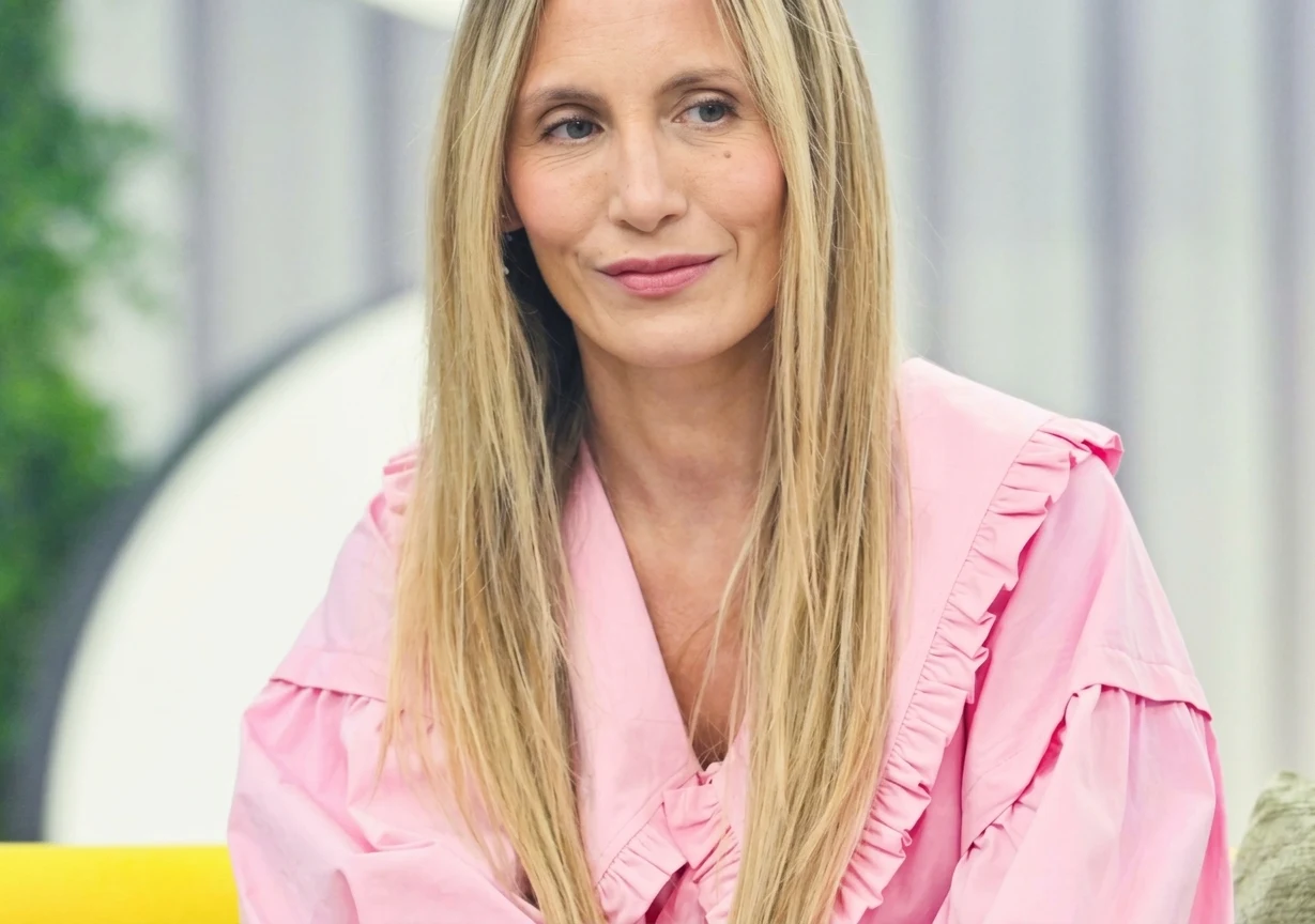 Pola Wiśniewska Pola Wiśniewska w różowej, falbaniastej bluzce, siedzi w studiu telewizyjnym na żółtej kanapie