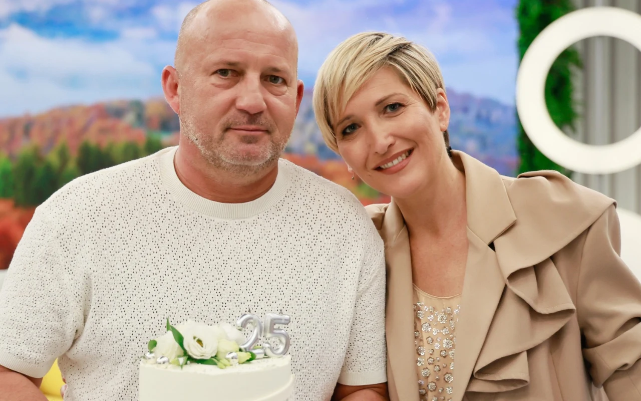 Piotr Królik i Magda Steczkowska Dwoje uśmiechniętych osób pozuje razem, trzymając biały tort z dekoracją i liczbą 25 na szczycie.