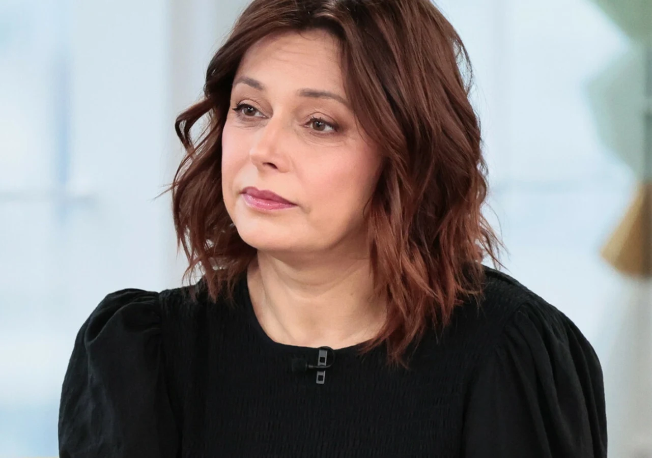 Renata Dancewicz Renata Dancewicz z krótkimi brązowymi włosami w czarnej bluzce z bufkami, zdjęcie z jasnego wnętrza studia telewizyjnego.